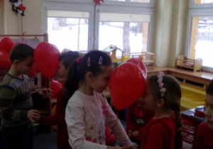 Dzieci tańczące w parach z balonami między główkami.